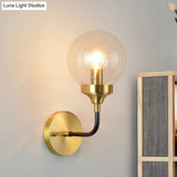 Clear Glass Globe Wall Sconce Light Fixture - Simple Brass With Curved Arm