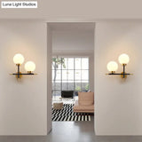 Post-Modern White Glass Sphere Wall Sconce With Brass Finish - 1/2 Bulbs